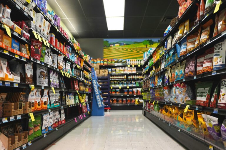 Retail store aisle with stocked shelves showing products across categories, representing inventory management in a multi-location business