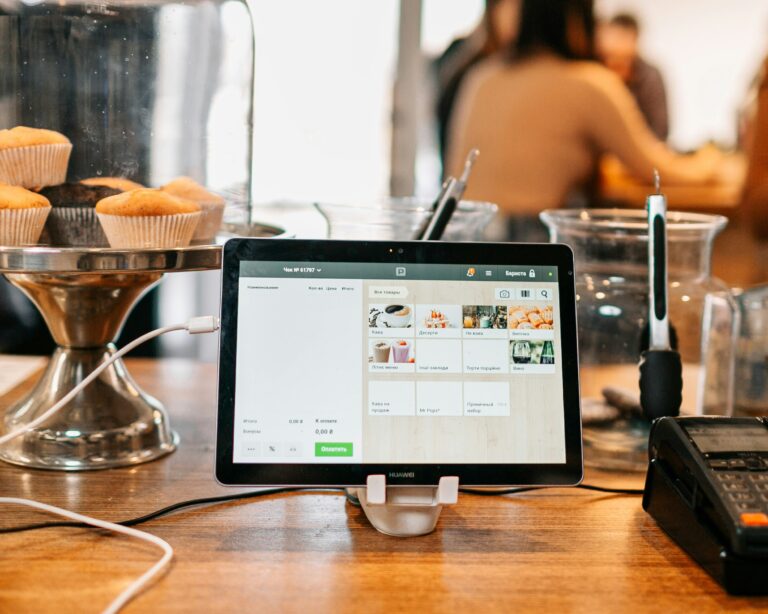 Tablet-based POS system in a café showing menu and billing interface with pastries on display